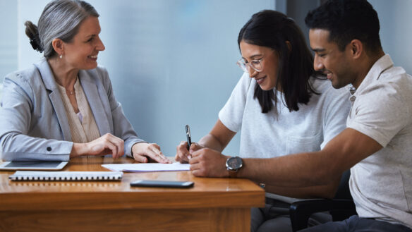 Couple signing documents with advisor.