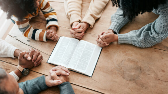 Hands clasped in group prayer.